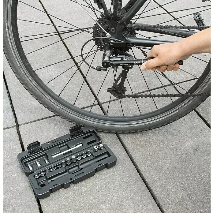 Wisent Drehmomentschlüssel - ¼″ Vierkant, 2 Nm - 20 Nm - Eine Hand benutzt einen schwarzen/silbernen Drehmomentschlüssel, um die Fahrrad-Gangschaltung einzustellen. Ein passendes Werkzeugset liegt daneben.
