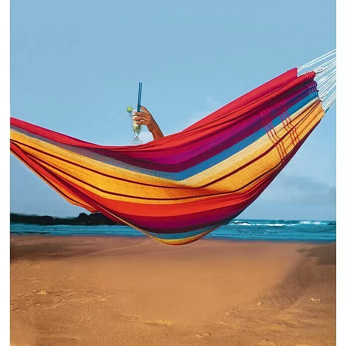 Amazonas Hängematte Barbados - Rainbow - Bunte gestreifte Hängematte am Strand, mit einer Person, die entspannt und einen Cocktail hält.