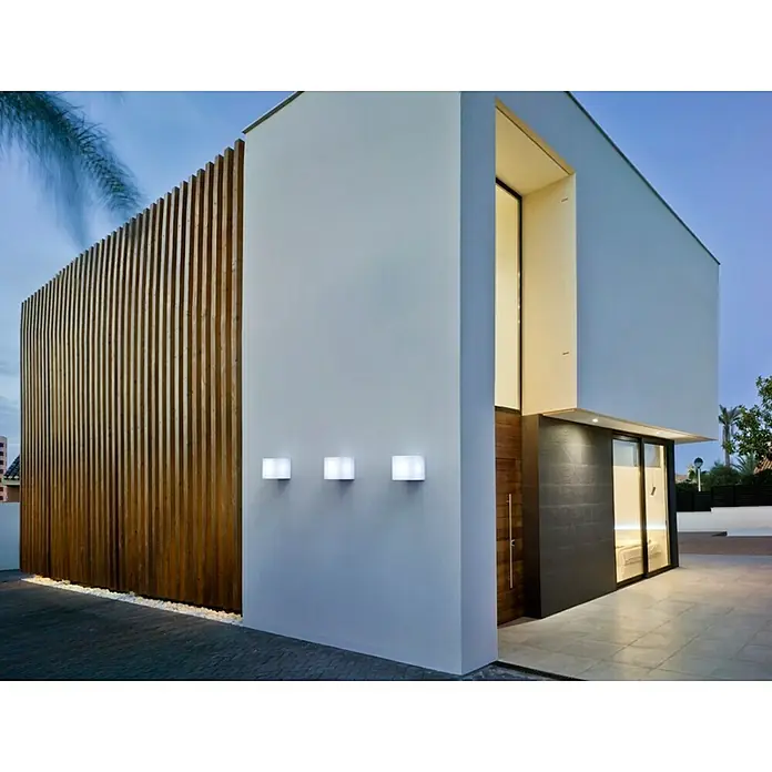 New Garden Lámpara solar LED decorativa Wally - Blanco, L x An x Al: 18 x 18 x 18 cm - Vista exterior de una casa moderna con revestimiento de madera y luces de pared cuadradas que crean un ambiente acogedor.