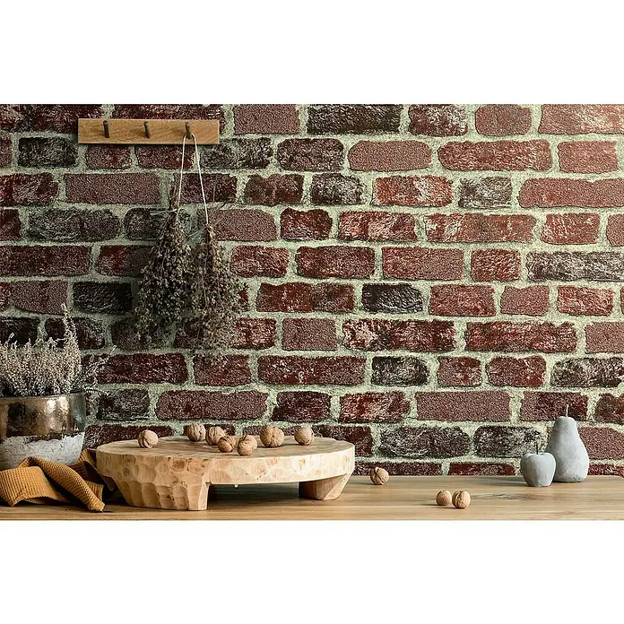 Marburg Sand & Stones Vliestapete Steinmauer II - Rot, Steinoptik, 10,05 x 0,53 m - Rustikale Küchendekoration mit einem Holzbrett, Nüssen und einem Topf mit Pflanzen vor einer Backsteinmauer.