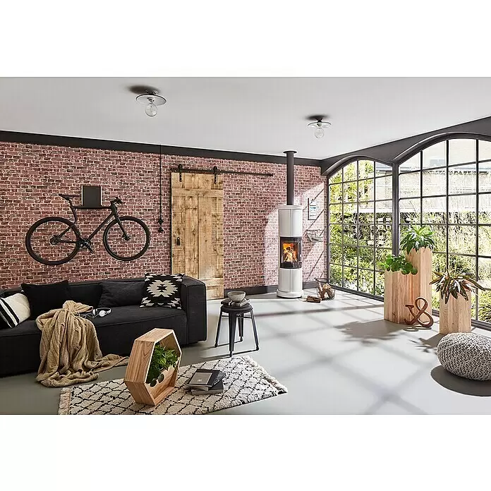 Marburg Sand & Stones Vliestapete Steinmauer II - Rot, Steinoptik, 10,05 x 0,53 m - Ein Wohnzimmer im Industriestil mit dunklem Sofa, Ziegelwand, weißem Holzofen und großen Bogenfenstern.