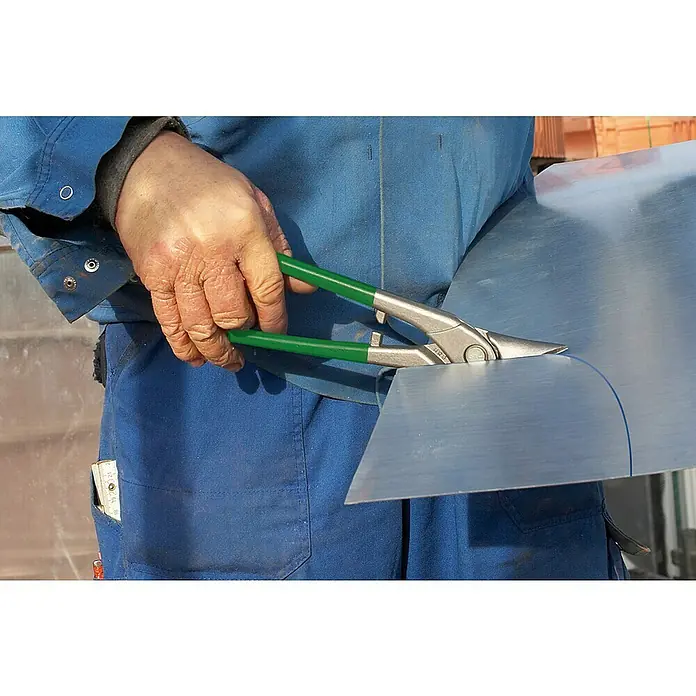 Wisent Tijeras Ideal - Largo: 260 mm, Corte a derecha - Una persona con ropa de trabajo azul corta chapa con tijeras para hojalata con mangos verdes. Una regla plegable está en el bolsillo.