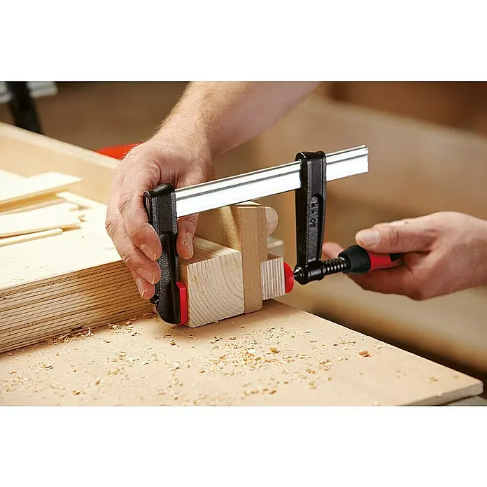 Bessey Schraubzwinge TP125S12BE - Spannweite: 1.250 mm, Spannkraft: 5.500 N, Ausladung: 120 mm - Detailaufnahme einer Holzbearbeitungsszene mit einer soliden Schraubzwinge, die präzise zwei Holzstücke zusammenhält, um eine feste Verbindung zu gewährleisten.