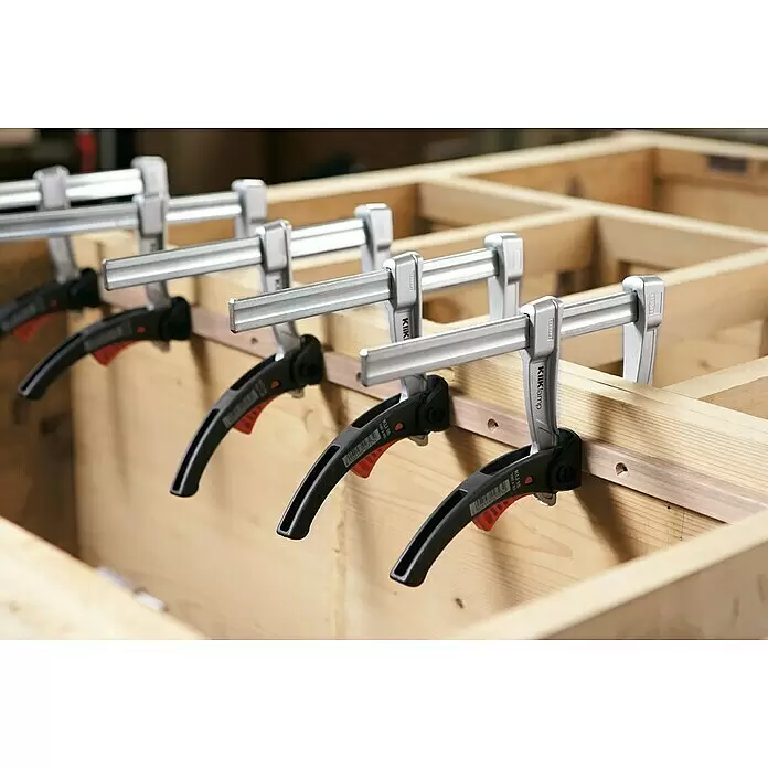 Bessey Hebelzwinge KliKlamp KLI 16 - Spannweite: 160 mm, Spannkraft: 1.200 N, Ausladung: 80 mm - Mehrere silberne und schwarze Bessey KliKlamp Zwingen fixieren Holzleisten in einem Holzrahmen.