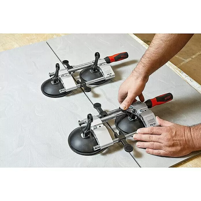 Bessey PS 55 -  - Zwei Hessey PS 55 Fliesen-Nivelliersysteme mit schwarzen Saugnäpfen, silbernem Metall und rot/schwarzen Griffen, die helle Fliesen ausrichten.