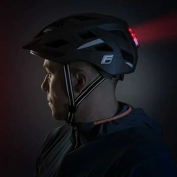 Fischer Fahrradhelm Urban Plus Brooklyn - S/M 52 - 59 cm, Schwarz - Nahaufnahme eines Mannes mit einem schwarzen Fahrradhelm mit integriertem Rücklicht für erhöhte Sicherheit und Sichtbarkeit.