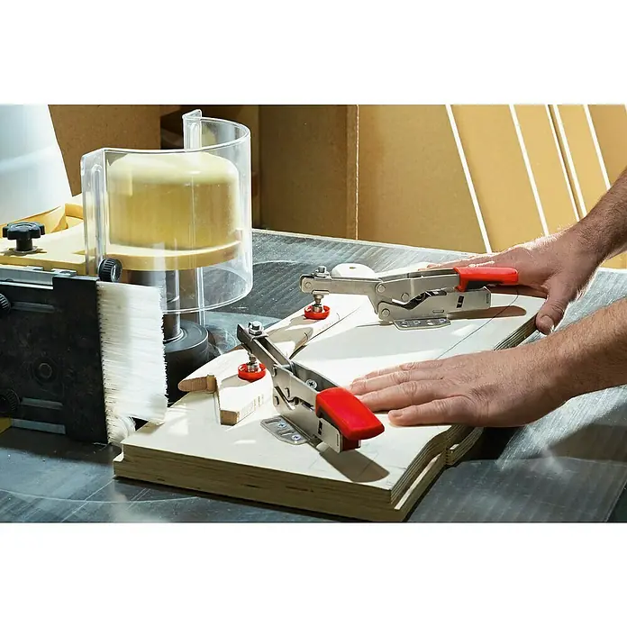 Bessey Waagrechtspanner STC-HH 20 - Spannweite: 20 mm, Spannkraft: 1.100 N - Eine Nahaufnahme einer Holzbearbeitungsmaschine mit Werkstücken, die mit roten Spannhebeln befestigt sind.