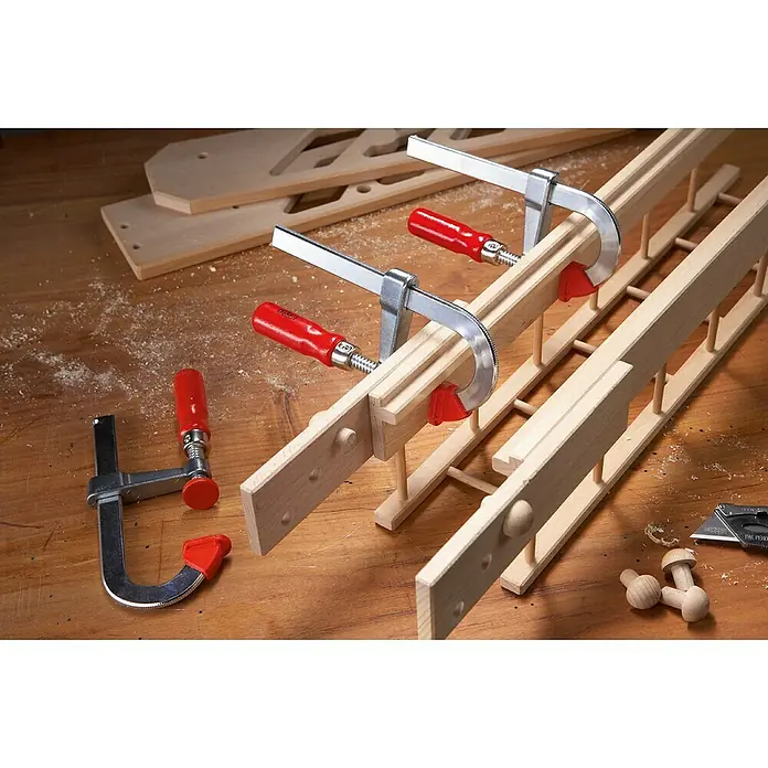 Bessey Schraubzwinge LMU15/5 - Spannweite: 150 mm, Spannkraft: 1.500 N, Ausladung: 50 mm - Detailaufnahme eines Holzprojekts mit Schraubzwingen, das handwerkliches Können und Präzision bei der Holzbearbeitung demonstriert.
