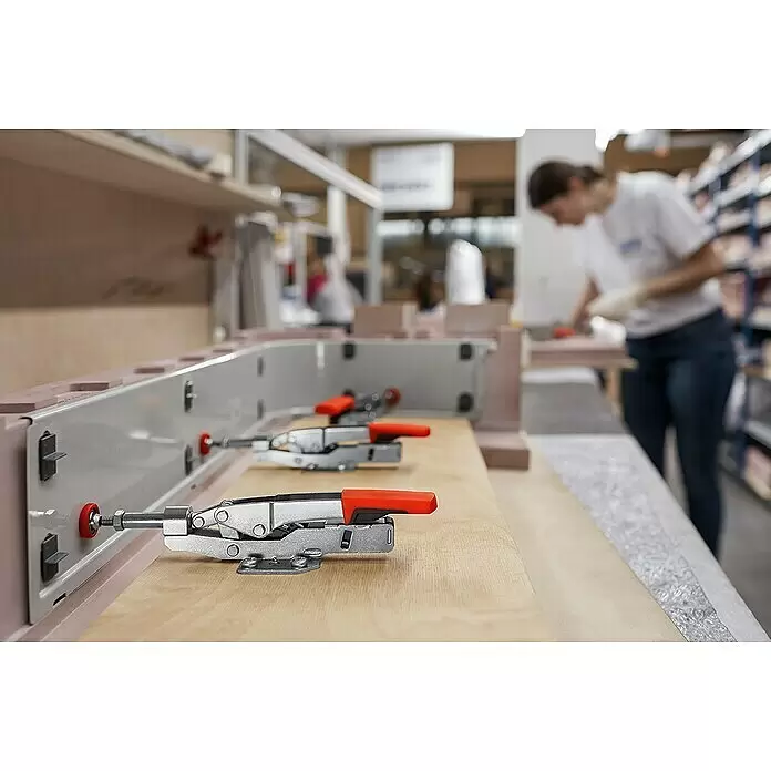 Bessey Schnellspanner STC-IHH25 - Spannweite: 16 mm, Spannkraft: 2.500 N - Metallische Spannzwingen mit roten Griffen befestigen eine gebogene Form auf einer Holzwerkbank.