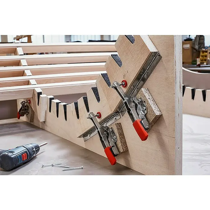 Bessey Waagrechtspanner STC-HH 20 - Spannweite: 20 mm, Spannkraft: 1.100 N - Nahaufnahme eines Holzbettrahmens mit Spannvorrichtungen und Schrauben. Die Bettrahmenkonstruktion aus hellem Holz ist mit Klemmen fixiert.