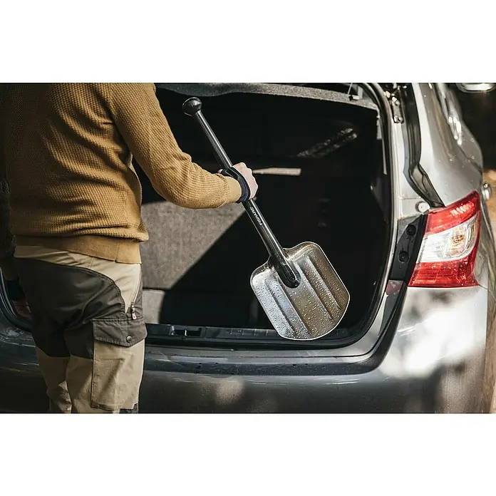 Fiskars Autoschaufel - Breite: 29 cm, Schwarz - Eine Person verstaut einen FISKARS Schneeschieber in einem grauen Kofferraum. Ideal für Winterwetter, um Ihr Auto freizuschaufeln.