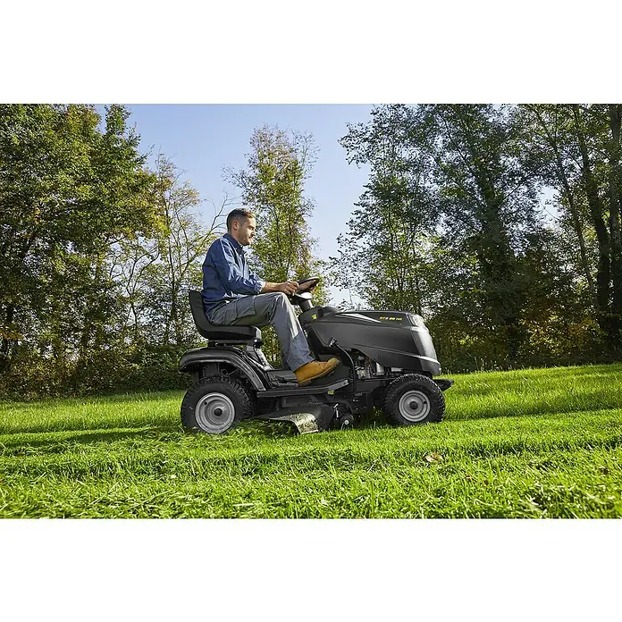 Alpina Rasentraktor AT3 98 HA - 7,1 kW, 414 cm³, Schnittbreite: 98 cm, Max. Flächenempfehlung: 5.000 m² - Ein Mann mäht den Rasen mit einem schwarzen Rasentraktor. Der Rasentraktor ist das Hauptprodukt im Bild.