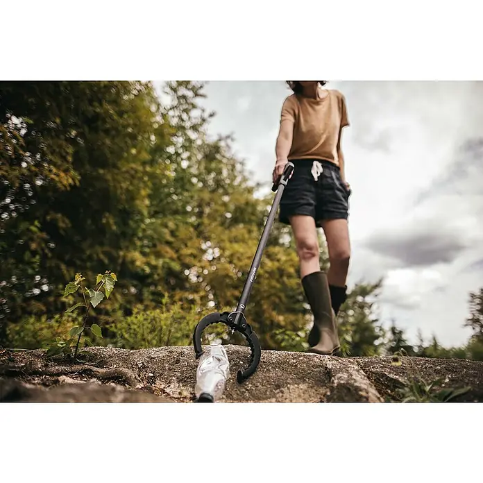 Fiskars Solid Greifer - Länge: 87,5 cm - Frau sammelt Müll mit einem Fiskars Greifer. Der Greifer hält eine Plastikflasche fest. Umweltfreundliche Müllsammlung.