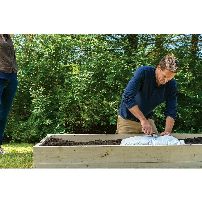 Fiskars Solid Mehrzweck-Schere SP320 - Länge: 20,6 cm - Mann öffnet Sack Pflanzerde mit einem Messer in einem Hochbeet. Die Erde wird für den Garten vorbereitet.