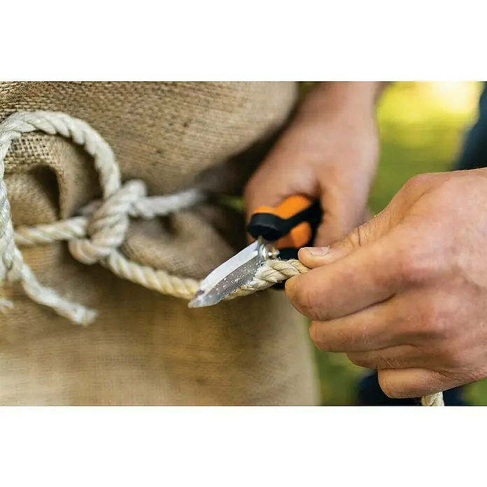 Fiskars Solid Mehrzweck-Schere SP320 - Länge: 20,6 cm - Ein Mann schneidet ein Seil mit einer kleinen Gartenschere, die orangefarbene Griffe hat, während er einen groben Leinengürtel trägt.
