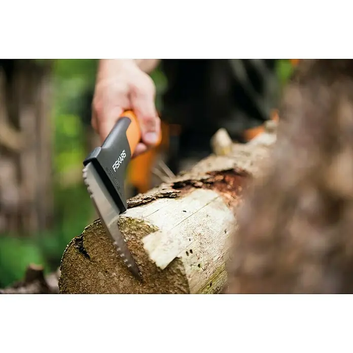 Fiskars WoodXpert Sappie XA2 - 35 cm - Nahaufnahme eines Fiskars-Werkzeugs, das zum Hacken eines Holzscheits verwendet wird, wobei der Fokus auf dem Werkzeug und dem Holz liegt.