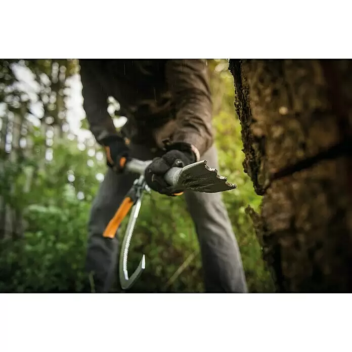 Fiskars WoodXpert Fällheber mit Wendehilfe M - 70 cm - Person hält silbernen Entrindungshaken mit orangefarbenem Griff, bereit Baum zu entrinden.
