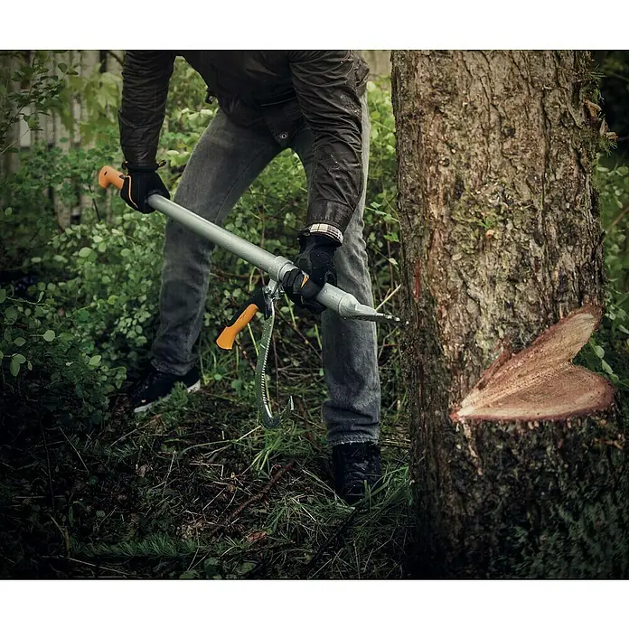 Fiskars WoodXpert Fällheber mit Wendehilfe M - 70 cm - Eine Person benutzt eine Fiskars Astschere, um einen Baumstamm zu schneiden. Das Werkzeug ist ideal für Gartenarbeiten.