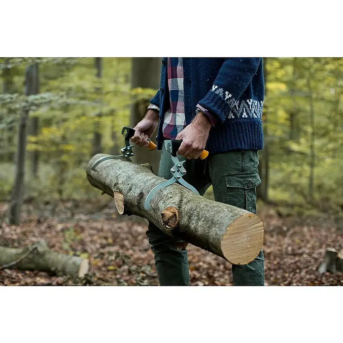 Fiskars WoodXpert Handpackzange - Länge: 38 cm - Ein Mann trägt mit einer Baumstamzange einen Baumstamm in einem Wald. Die Zange erleichtert das Heben des schweren Stammes.