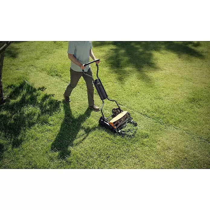 Fiskars Spindelmäher StaySharp Max - Schnittbreite: 46 cm - Eine Person schiebt einen schwarz-orangen Spindelmäher über einen Rasen.