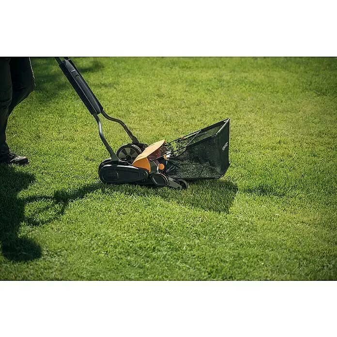 Fiskars Spindelmäher StaySharp Max - Schnittbreite: 46 cm - Schwarz-orangener Spindelmäher mit Grasfangkorb, von einer Person geschoben.