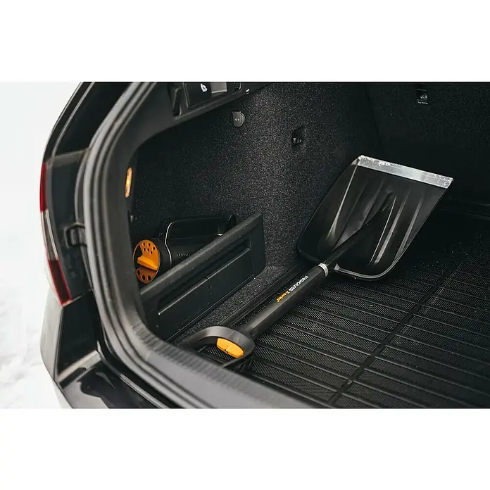 Fiskars X-series Schneeschaufel - Breite: 29 cm, Teleskopstiel - Eine Fiskars X-series Schneeschaufel liegt im Kofferraum eines Autos und ist bereit für den Einsatz im Winter. Praktisch und platzsparend.