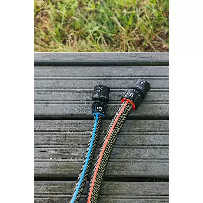 Fiskars FiberComp Schlauchanschluss Stop - ½″ / ⁵⁄₈″ - Zwei nasse Gartenschlauch-Schnellverbinder mit Schläuchen (blau und orange gestreift) auf einer Holzterrasse, mit Wasserstoppfunktion.
