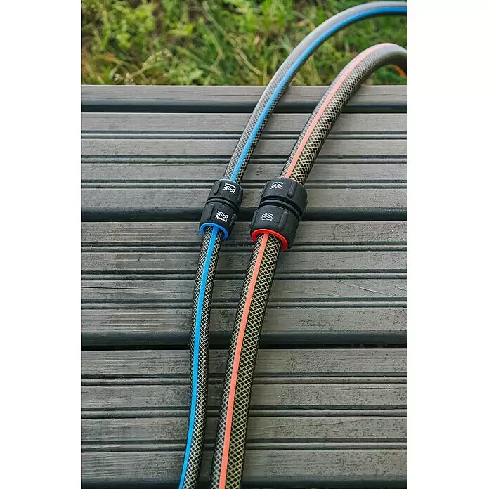 Fiskars FiberComp Reparator - Passend für: ½″-Schläuche Ø 13 mm, ⁵⁄₈″-Schläuche Ø 15 mm - Zwei Gartenschläuche, einer mit blauem und einer mit orangefarbenem Streifen, mit passenden Anschlüssen, auf Holz liegend.