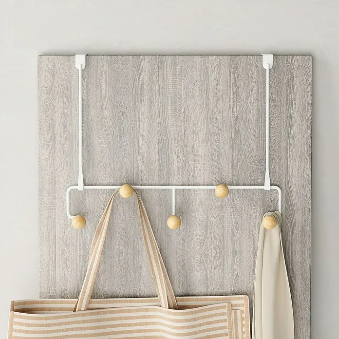 Umbra Türhaken Estique - L x B x H: 10,2 x 38,6 x 30,5 cm, Anzahl Haken: 5 Stk. - Ein weißer Türhänger mit fünf Holzkugeln als Haken, an dem eine gestreifte Tasche und ein Tuch hängen.