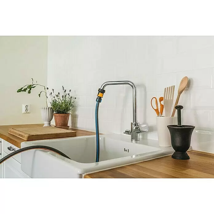 Fiskars FiberComp Hahnverbinder - Gewindegröße Wasserhahn: M 22 x 1 - Ein blau-schwarzer Gartenschlauch mit gelbem Anschluss an einem Chrom-Küchenhahn, der ins weiße Spülbecken reicht.