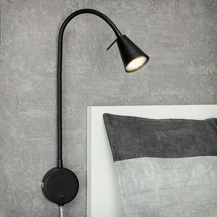 Briloner LED-Wandstrahler Tusa - 4 W, L x B x H: 5,8 x 20,5 x 45 cm, Schwarz, Warmweiß - Nahaufnahme einer modernen schwarzen Schwenkarm-Wandleuchte mit LED-Beleuchtung, die neben einem Bett montiert ist.
