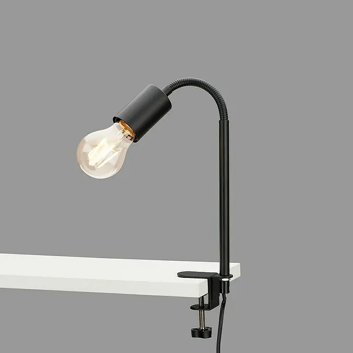 Briloner Klemmleuchte Krampo - 10 W, Farbe Gehäuse: Schwarz - Nahaufnahme einer verstellbaren Klemmleuchte mit Glühbirne, die an einer weißen Oberfläche befestigt ist, ideal für Arbeitsbereiche.