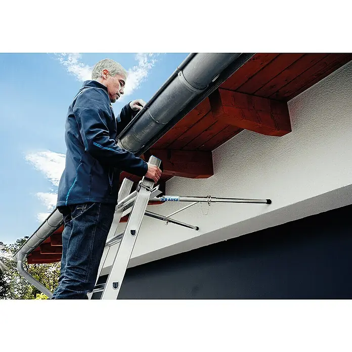Krause Combi AbstandhalterGeeignet für: Holmquerschnitt 64 x 25 mm bis 97 x 25 mm, Aluminium - Eine Person benutzt eine Krause Leiter mit Abstandhalter, um an einer Dachrinne zu arbeiten. Sichere und praktische Lösung für Arbeiten in der Höhe.