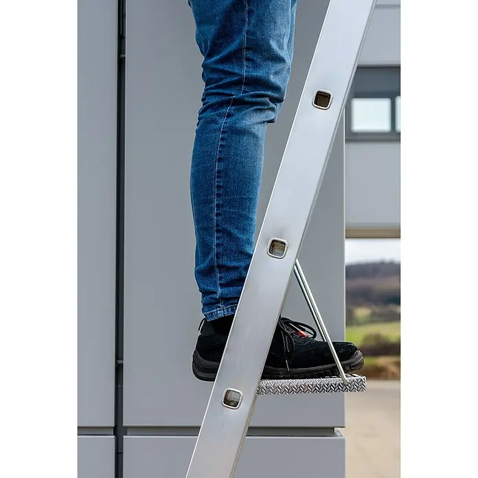 Krause Trittablage - L x B x H: 450 x 340 x 70 mm - Detailaufnahme einer Aluminiumleiter mit Person, die blaue Jeans und schwarze Schuhe trägt.