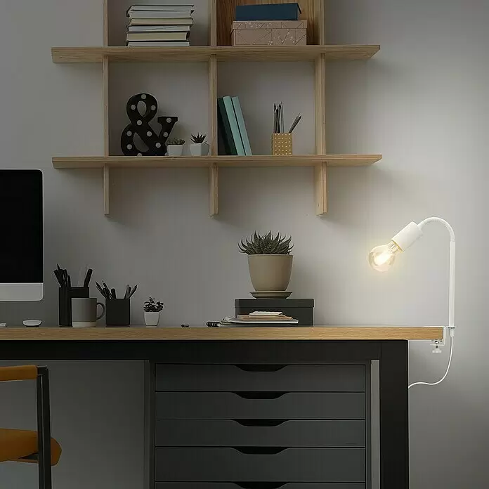 Briloner Klemmleuchte Krampo - 10 W, Farbe Gehäuse: Weiß - Weiße, flexible Schreibtischlampe mit sichtbarer Glühbirne, an einem Holzschreibtisch im Home-Office befestigt.