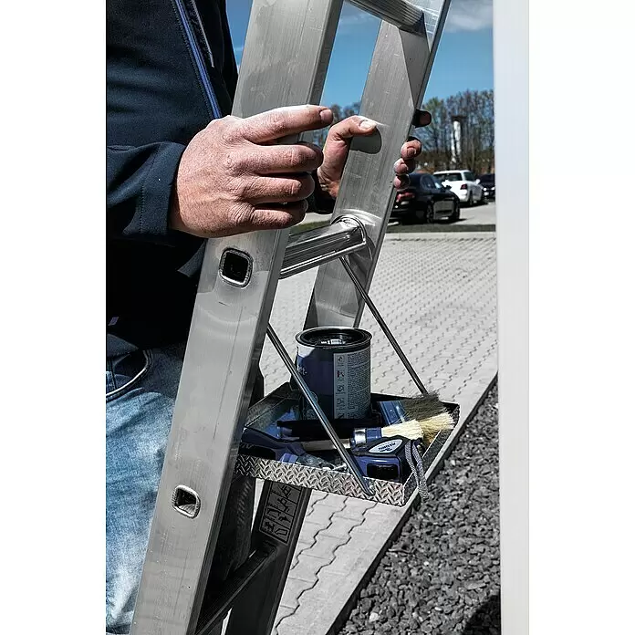 Krause Trittablage - L x B x H: 450 x 340 x 70 mm - Eine Person hält eine silberne Aluminiumleiter mit einer Werkzeugablage aus Riffelblech, gefüllt mit Farbe, Pinseln und Maßband, bereit zur Arbeit.
