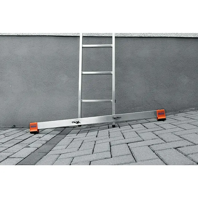 Krause Traverse - L x B x H: 1.250 x 110 x 70 mm, Metall - Das Bild zeigt eine Aluminiumleiter mit orangenen Füßen, die an einer grauen Wand auf Pflastersteinen steht. Sie ist kompakt und sicher für verschiedene Arbeiten.
