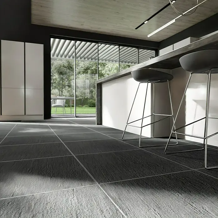 Terrassenfliese Slate Black - 60 x 60 x 2 cm, Schwarz, Matt - Eine moderne Küche mit grauen Fliesen, einer weißen Kücheninsel und zwei Barhockern, die ein stilvolles und minimalistisches Ambiente schafft.