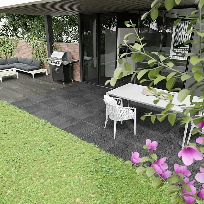 Terrassenfliese Slate Black - 60 x 60 x 2 cm, Schwarz, Matt - Ein Außengrill und eine Sitzgruppe auf einer Terrasse mit Blick auf einen gepflegten Rasen. Der Grill ist das Highlight des Entspannungsbereichs.