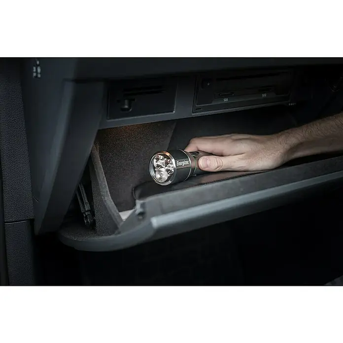 Energizer Linterna Visión - 250 lm - 1.000 lm, IPX4 - Imagen de una mano colocando una linterna Energizer en la guantera oscura de un coche.