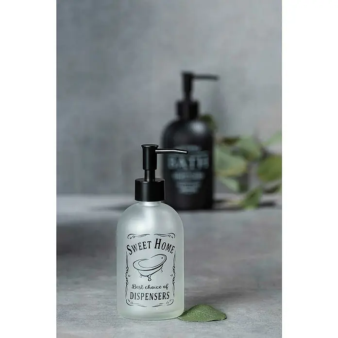 Wenko Seifenspender Sweet HomeGlas, Transparent - Das Bild zeigt einen Seifenspender mit der Aufschrift "Sweet Home", der sich ideal für die Badezimmerausstattung eignet, und ist mit einem schwarzen Spenderkopf versehen.