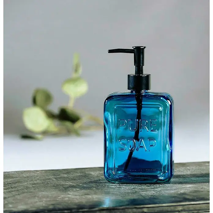 Wenko Seifenspender Pure SoapGlas, Blau - Blauer Seifenspender mit schwarzem Pumpkopf. Der Behälter hat die Aufschrift "Pure Soap" und steht auf einer Holzoberfläche.