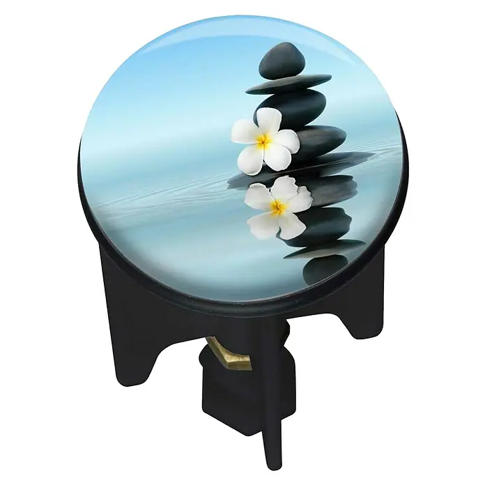 Wenko Excenterstopfen Saguna - Wellness, Durchmesser: 3,9 cm - Runder Tisch mit Zen-Steinen und Frangipani-Blüten auf der Oberfläche, ideal für Entspannung und Meditation.