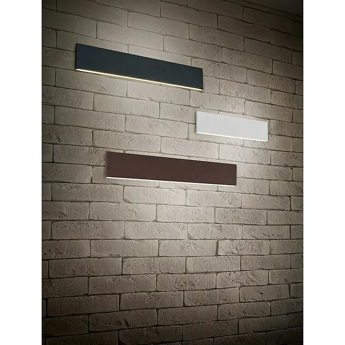 Trio Leuchten LED-Wandleuchte Concha - 9 W, L x B x H: 4,5 x 47 x 8 cm, Anthrazit, Warmweiß - Wandleuchten in Schwarz, Weiß und Braun an einer Ziegelwand.