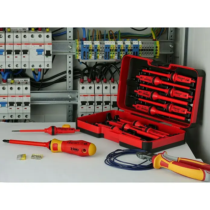 Felo Schraubendreher-Set E-Smart VDE - 14 -tlg. - Elektriker-Werkzeugset von Felo, inklusive Schraubendrehern, Zangen und Kabeln, vor einem Sicherungskasten für Elektroinstallationen.