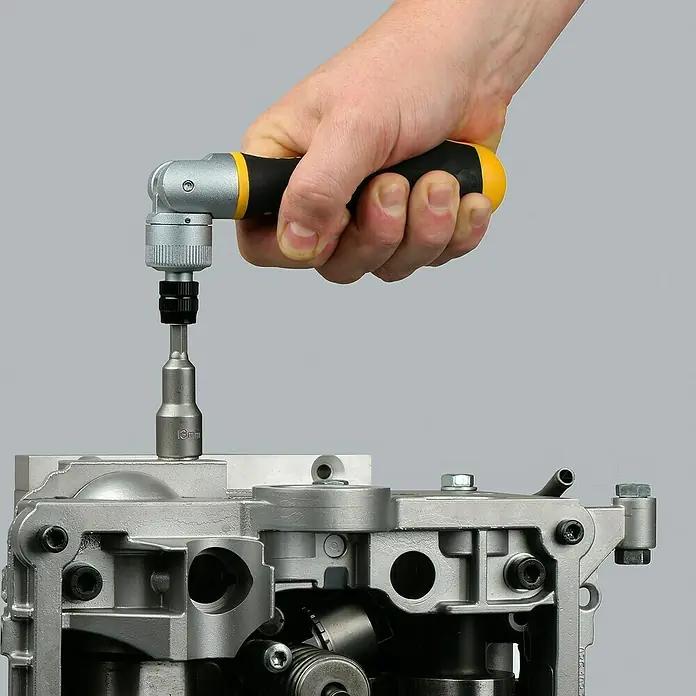 Felo Steckschlüsseleinsatz-Set ERGONIC® K - ¼″, 20 -tlg. - Eine Hand hält einen Wera Zyklop Speed Schraubendreher mit Nuss, der an einem silbernen Maschinenteil angebracht ist.