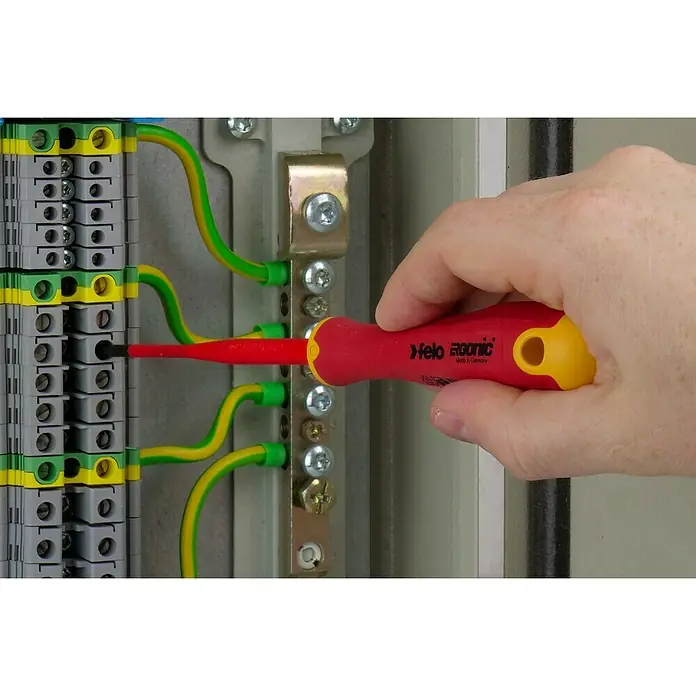 Felo Schraubendreher-Set ERGONIC® VDE E-Slim - 4 -tlg., Geeignet für: TORX®-Schrauben - Aufnahme einer Hand, die mit einem Felo Ergoonic Schraubendreher an einem elektrischen Bauteil arbeitet. Das Werkzeug ist rot-gelb und für Elektroarbeiten geeignet.