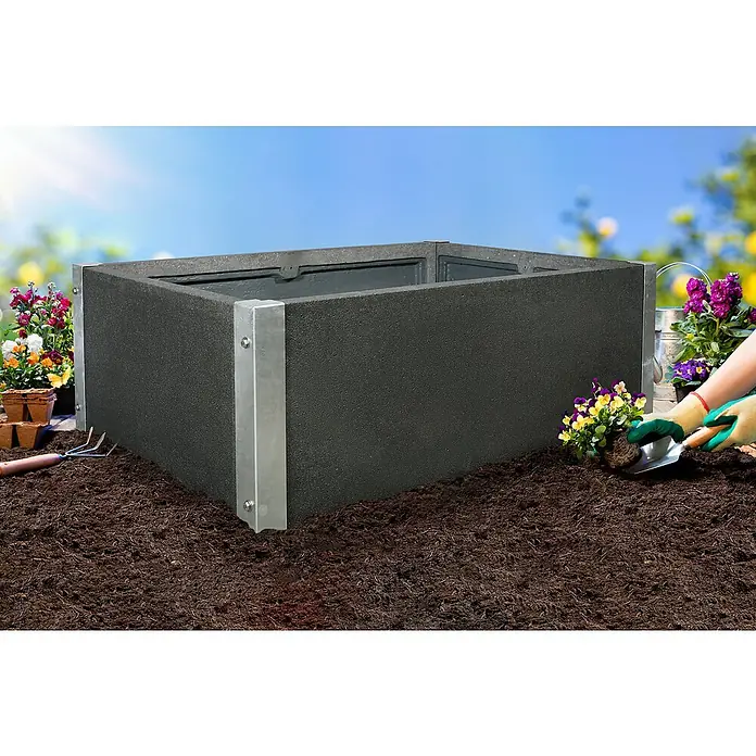 Hochbeet Loftico - 120 x 76 x 40 cm, Beton, Grau - Das Bild zeigt ein schwarzes Hochbeet mit silbernen Eckverstärkungen, umgeben von Erde und Blumen, bereit für die Bepflanzung.