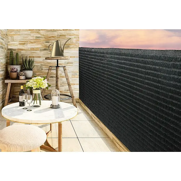 Gardol Balkonsichtschutz Raffia - Grau, 300 x 90 cm - Stilvoller Balkonbereich mit Tisch, Stuhl, Pflanzen und einem eleganten, schwarzen Sichtschutz für Privatsphäre und Ästhetik.