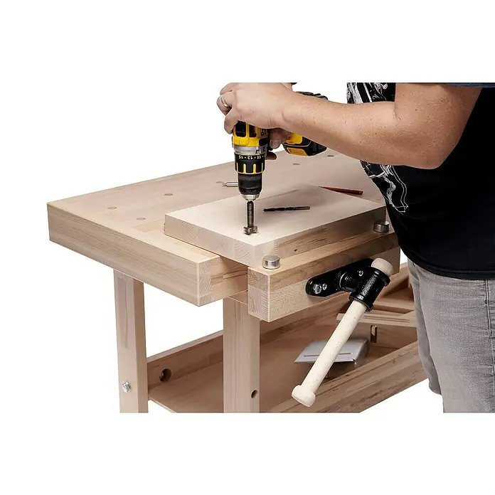 Ramia Hobelbank Advanced 2000 - L x B: 2.000 x 650 mm, Arbeitshöhe: 850 mm, Holz - Eine Person benutzt eine gelbe Bohrmaschine, um ein Loch in ein Stück Holz zu bohren, das auf einer Werkbank liegt.